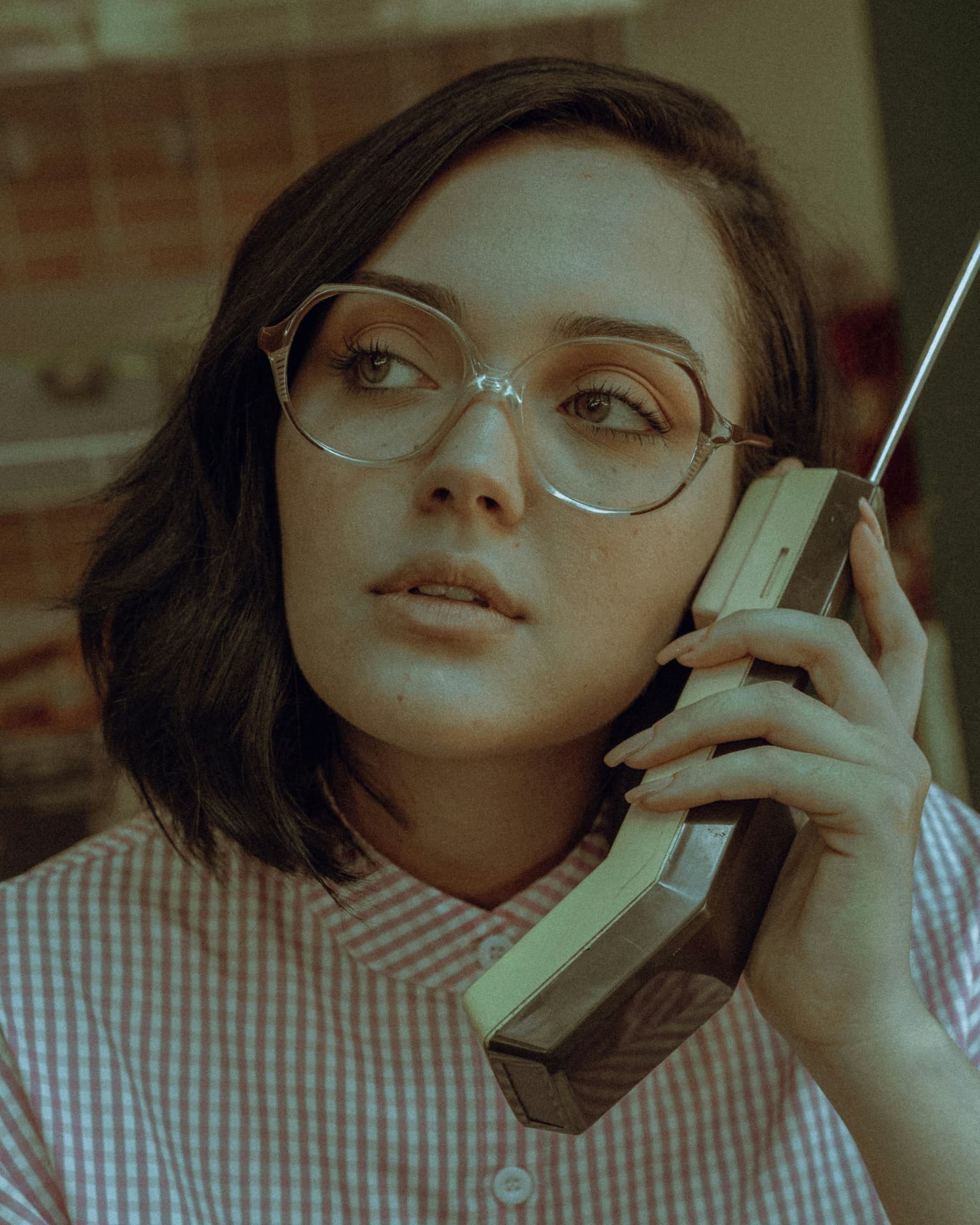Creative woman in vintage glasses talking on a retro phone